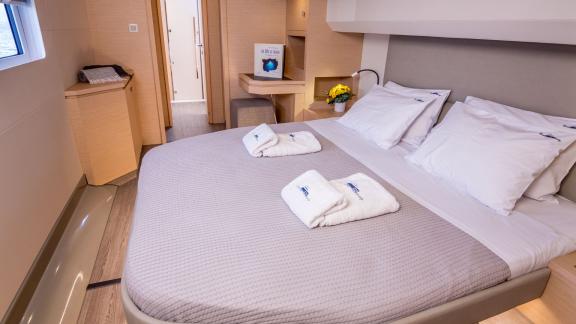 Tastefully decorated cabin with a large bed, desk, and modern amenities on a luxurious catamaran.