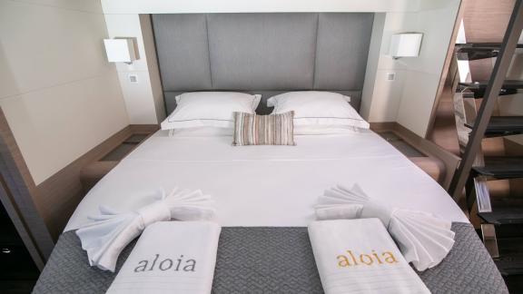 Luxuriöses Doppelbett im Hauptschlafzimmer des Katamaran Alonia mit personalisierten Handtüchern.