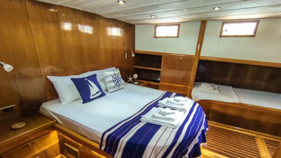 Cabin with double bed, nautical decor, and additional single bed on Gulet Cagan 2.