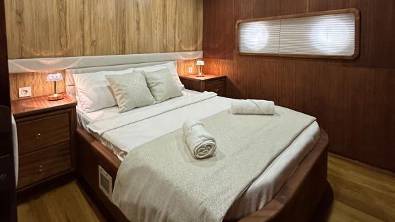 Elegant bedroom with a double bed and warm wood decor on the Gulet yacht.