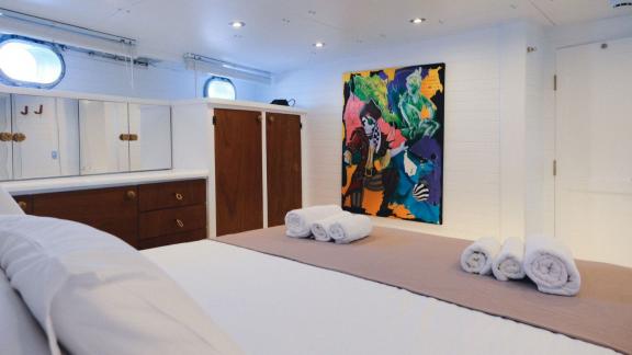 Modern bedroom with colourful wall art and towels on a gulet.