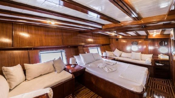 Large master cabin with a comfortable bed and seating area on the Gulet Optimist in Bodrum.