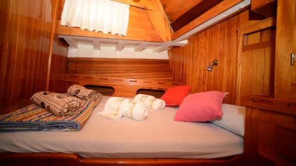 Cozy cabin with a double bed, colorful pillows, and towels.