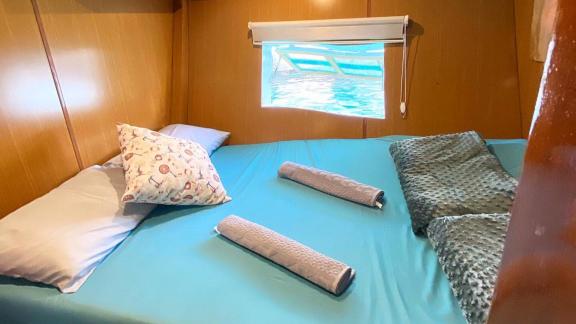 Cozy cabin on Gulet Avuncan with double bed and window overlooking the clear waters of the Aegean Sea.