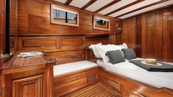 Wood-paneled cabin with a comfortable bed and ample storage on Serenad A.