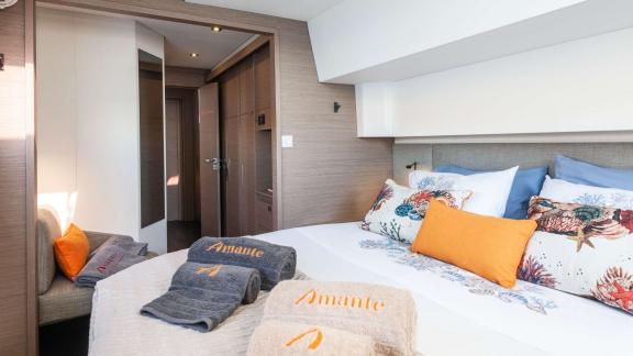 Cozy bedroom on a catamaran, featuring decorative pillows and towels.