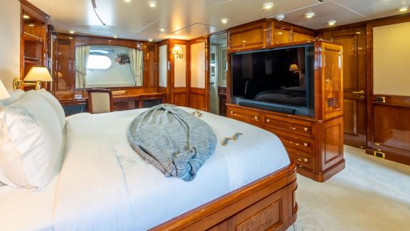 Geräumiges Schlafzimmer auf der Yacht Stella Fiera mit komfortablem Bett und großem Fernseher.