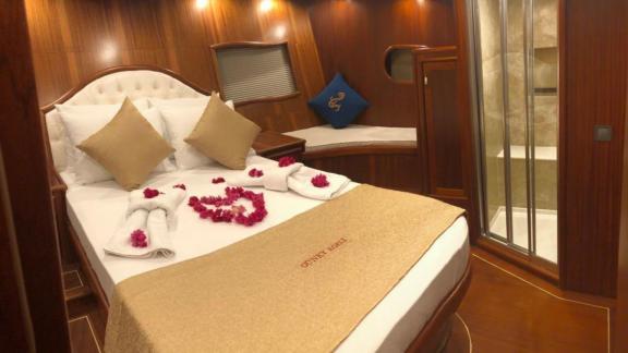 Luxurious cabin with double bed, decorative towels, and access to a private bathroom.