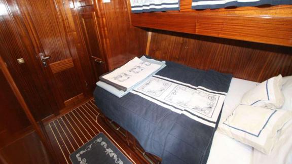 Stylish double cabin on Gulet Miramare with dark wood paneling and nautical-themed bedding.