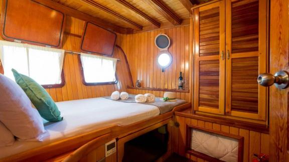 Cozy wood-paneled cabin with a double bed on a Gulet yacht. Luxurious retreat at sea.