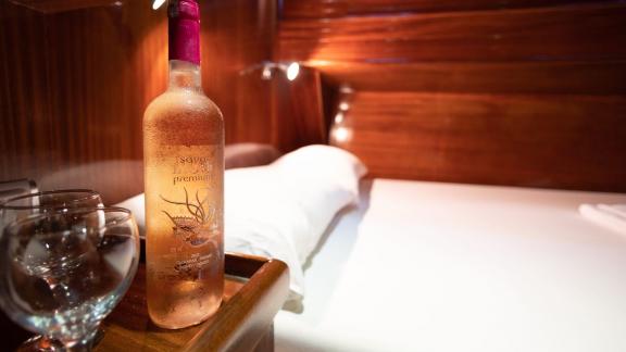 Close-up of a wine bottle and glasses on a bedside table in the cabin of Gulet Erden.