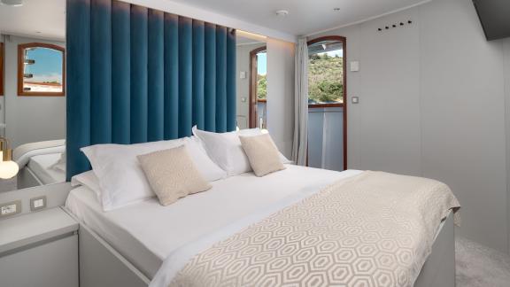 Bright and modern cabin on the Bellezza yacht with a large bed and views of nature.