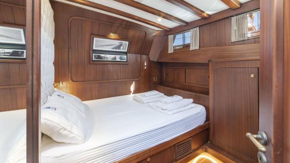 Cabin of the gulet yacht Jasemin 1 with cosy double bed and wooden furnishings.