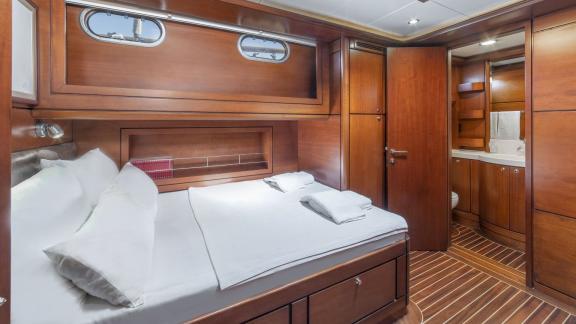 Luxuriöse Kabine mit Doppelbett, Holzverkleidung und eigenem Badezimmer auf einer Segelyacht.