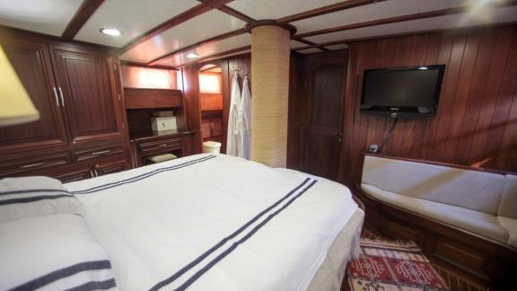 A spacious and luxurious cabin on board the Gulet Dulcinea with a large bed, wardrobes and a seating area.