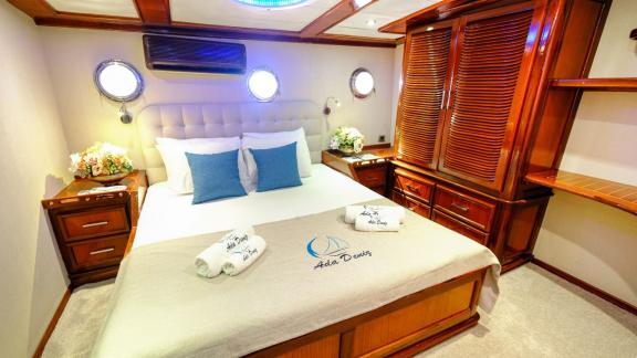 Eine elegante Kabine auf einer Yacht mit einem großen Bett und Holzmöbeln.