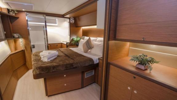 Spacious cabin with a double bed, wood paneling, and an adjoining bathroom on the Daphne catamaran.