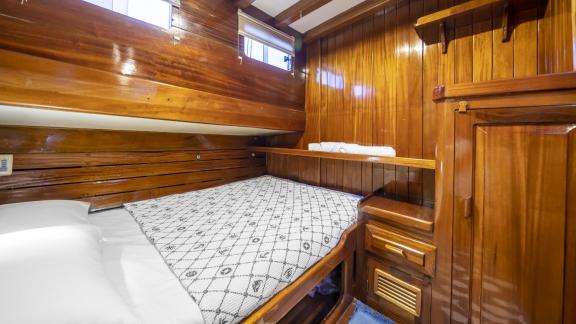 The double cabin features a bed with a patterned cover, wooden walls, and storage space.