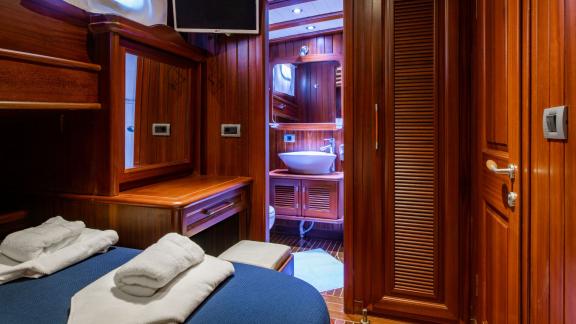 Comfortable cabin of the 24-meter Gulet Sani Kaptan 2 with private bathroom and wood paneling in Bodrum, Turkey.