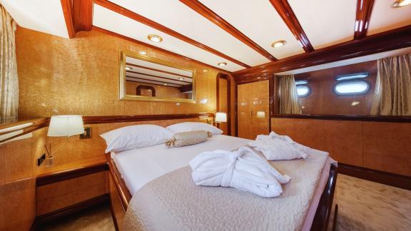 The luxurious bedroom of motor yacht Custom Blanka features a wide bed and elegant decor.