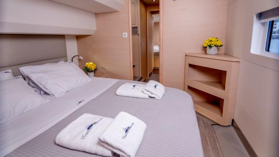 Bright cabin on a catamaran with a large bed, window, and access to an elegant bathroom.