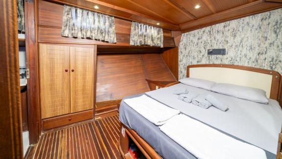 Relax in the elegant bedroom of Gulet S Nur 1 featuring stylish wooden wardrobes and a cozy bed.