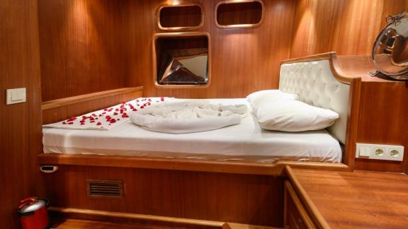 A comfortable sleeping cabin on the Gulet Anıl Kaptan 1 with wood paneling and romantic decoration.