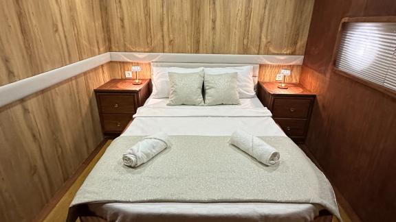 Comfortable bedroom with double bed and warm wood walls on the Gulet yacht.