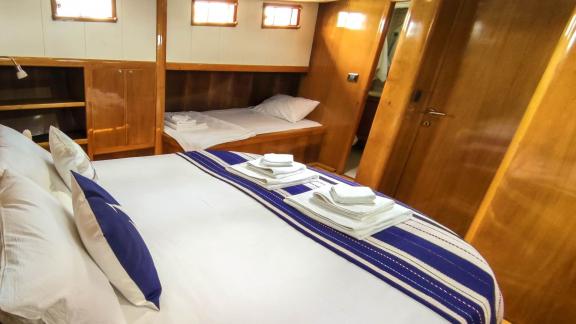 Cabin on Gulet Cagan 2 with a comfortable double bed and additional single bed, nautically themed.