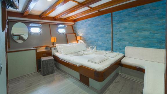 Comfortable cabin with double bed, blue wall decoration, porthole windows and maritime details.