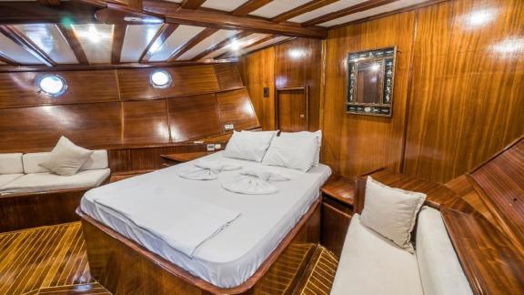 Large master cabin with a comfortable bed and sofa on the Gulet Optimist in Bodrum.