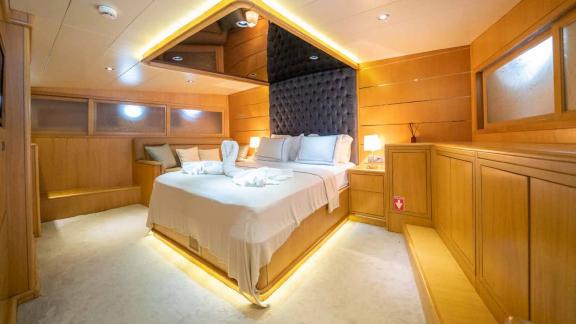 A luxurious cabin on a traditional Turkish gulet, equipped with a large, comfortable bed and stylish lighting.