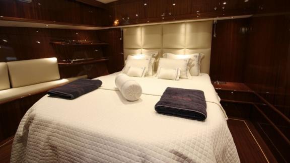 Elegant cabin of the Gulet Didi with large bed, wooden panelling and bench seat.