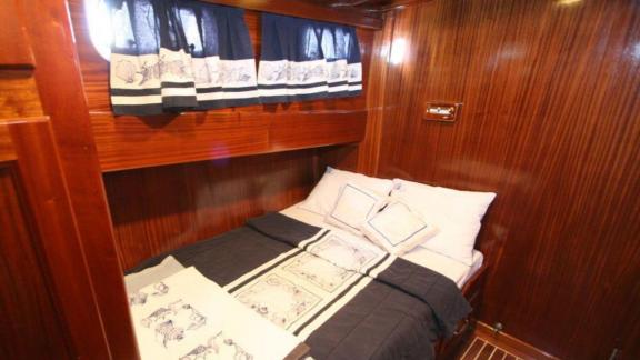 Double cabin on Gulet Miramare with elegant dark wood paneling and nautical-themed bedding.