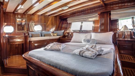 Elegant cabin on the gulet Entre Cielos with large bed, seating area and elegant wooden furnishings for maximum comfort.