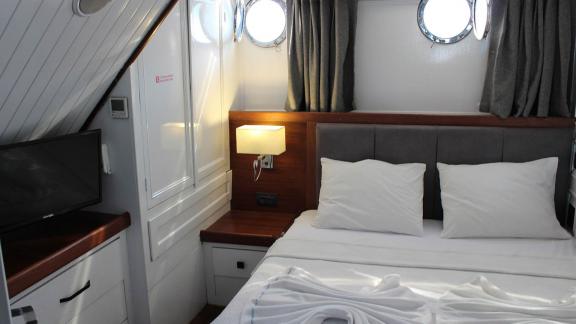 Stilvolle Kabine der Grande Mare mit Doppelbett, TV und gemütlicher Beleuchtung. Perfekt für luxuriöse Yachtcharter in B