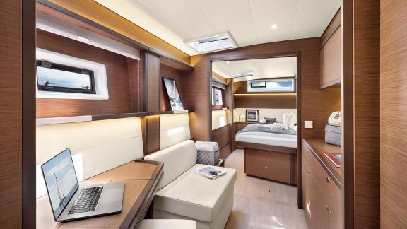 Luxurious cabin with a desk, seating area, and double bed, featuring modern design and natural light.