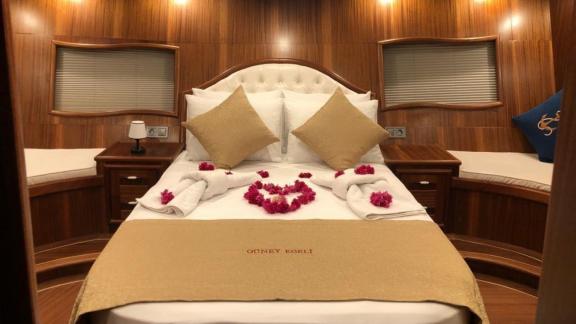 Luxurious cabin with a double bed, decorative towels, and wooden furniture.