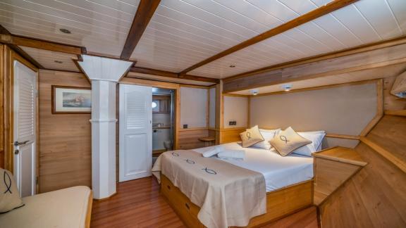 A cosy bedroom on the gulet yacht Amazon Solo with double bed, wooden furniture and direct access to the bathroom.