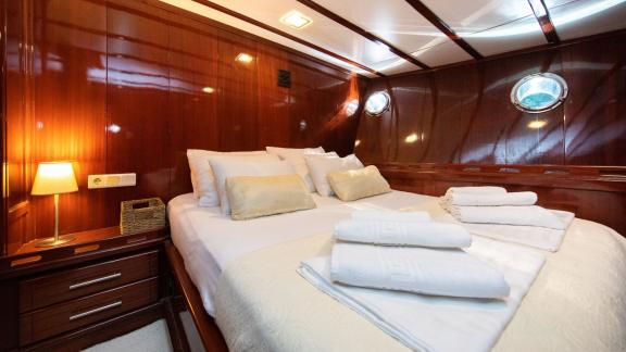 Tastefully furnished cabin of the Gulet Vivere with comfortable bed, wood panelling and soft lighting.