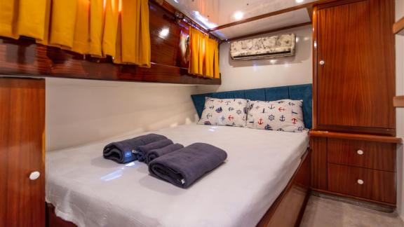 Third guest cabin of Gulet Lycian Sirius featuring a double bed, wooden furniture, orange curtains, and air conditioning