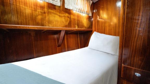 Cabin of Gulet Lina 2 with a single bed, wood paneling, and soft lighting.