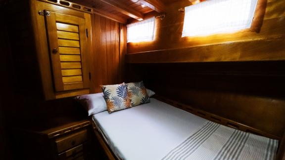 A cozy cabin on Gulet Pronto White, featuring warm wood decor and a comfortable double bed.