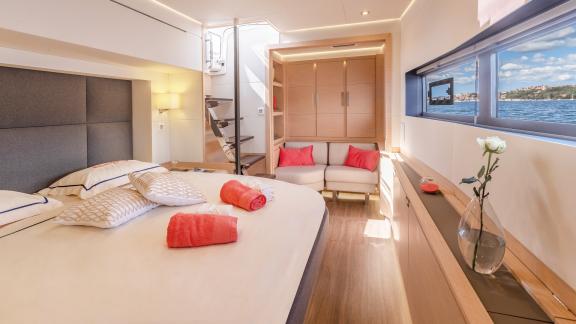 Modern bedroom with light wooden furniture and soft textiles on the Serenissima catamaran.