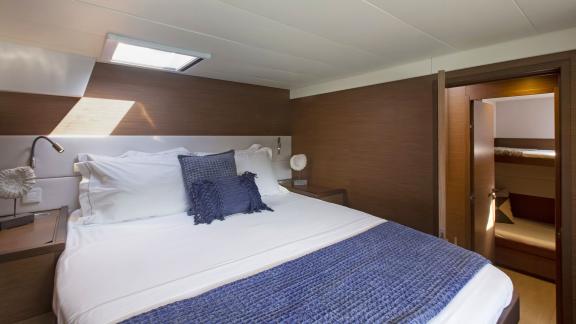 The comfortable cabin of the Lagoon 560 in Athens features a large double bed and warm light streaming through a skyligh