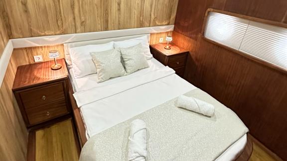 Stylish bedroom with double bed and elegant wooden furniture on the Gulet yacht.