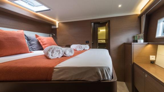 Modernes Schlafzimmer im Katamaran Nomad mit orangefarbenen Akzenten und luxuriösem Komfort.