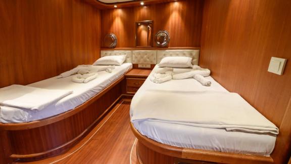 A comfortable twin cabin on the Gulet Anıl Kaptan 1 with elegant wood paneling and pleasant lighting.