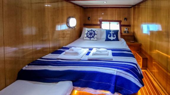 Cabin on Gulet Cagan 2 with double bed, blue bedspread, and nautical-themed pillows.