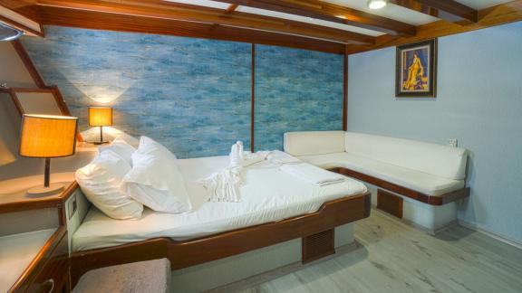 Comfortable cabin with double bed, blue wall decoration, cosy seating area and soft lighting.